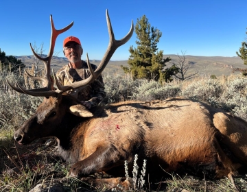 A nonresident Wyoming hunter posing with his bull elk after the hunt